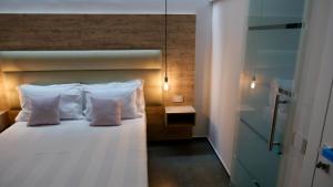 1 dormitorio con 1 cama con almohadas blancas en Oneira Rooms, en Agrigento