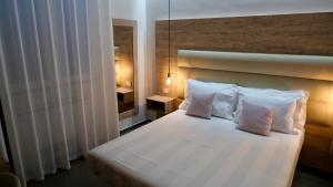 um quarto com uma cama branca e 2 almofadas em Oneira Rooms em Agrigento