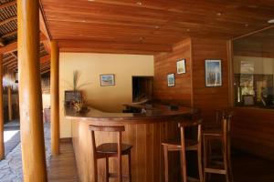 un bar en un restaurante con paredes de madera y taburetes de madera en Hôtel **** Palissandre Côte Ouest, en Morondava