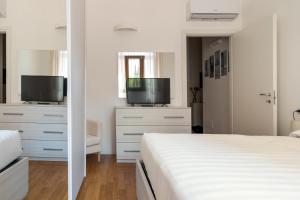 een witte slaapkamer met een bed en een televisie bij Duomo Apartment - Diaz in Milaan