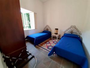 een kamer met 2 blauwe bedden en een raam bij RELAIS COUNTRY HOUSE - TERRACE on AEOLIAN ISLANDS in Acquedolci