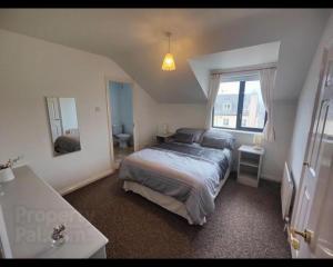 ein Schlafzimmer mit einem Bett und einem großen Fenster in der Unterkunft Portrush Penthouse Stunning Harbour & Atlantic Views only 2 mins walk to Harbour & Ramore in Portrush