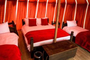 two beds in a room with orange curtains at Warwick Castle Hotel & Knight's Village in Warwick