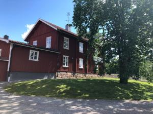 een rood huis met een boom ervoor bij Turistgården Töcksfors in Töcksfors