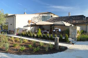 a building with a patio with tables and umbrellas at Logis- Hôtel Spa Restaurant l'Epicurial in Saint-Pey-de-Castets