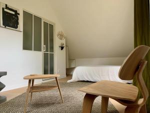 a bedroom with a bed and a chair and a table at La Maison Vivante, chambres d'hotes au coeur du Perche in Les Étilleux