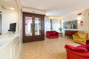 sala de estar con sillas rojas y TV en Hotel Bella Venezia, en Venecia
