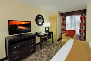 Habitación de hotel con cama, escritorio y TV. en Holiday Inn Express Augusta Downtown, an IHG Hotel, en Augusta