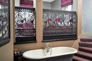 a bathroom with a tub, sink, and mirror at Malmaison Dundee in Dundee