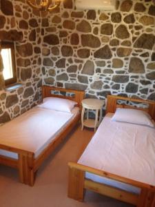 two beds in a room with a stone wall at Loutra Olive Garden Stone House #2 in Mandrákion