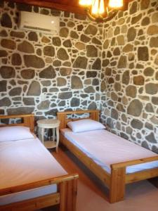 a room with two beds and a stone wall at Loutra Olive Garden Stone House #2 in Mandrákion