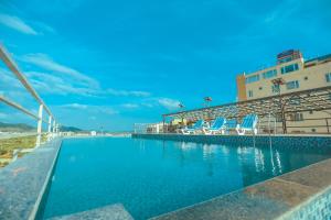 a swimming pool next to a beach with chairs and a building at Hotel Yois in Udaipur