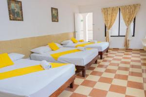 4 Betten in einem Zimmer mit kariertem Boden in der Unterkunft OYO Hotel Marías,Aeropuerto Internacional de Chetumal in Chetumal