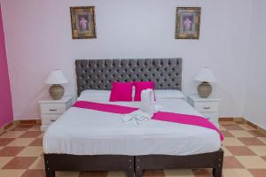 ein Schlafzimmer mit einem großen Bett mit rosa Kissen in der Unterkunft OYO Hotel Marías,Aeropuerto Internacional de Chetumal in Chetumal