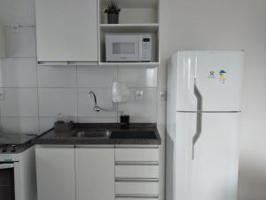 a white kitchen with a sink and a refrigerator at Apartamento em Boa Viagem in Recife