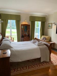 Un dormitorio con una gran cama blanca y una ventana en Borthwnog Hall en Dolgellau