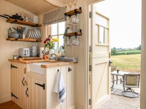 uma cozinha em plano aberto com um lavatório e uma janela em High Grounds Shepherd's Hut em Ashbourne