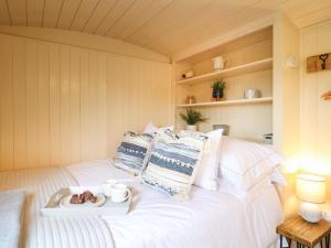 Una cama blanca con una bandeja de comida. en High Grounds Shepherd's Hut en Ashbourne