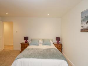 een witte slaapkamer met een bed en twee nachtkastjes bij Dorset View in Blandford Forum