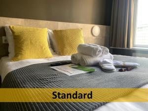 een bed met handdoeken en schoenen erop bij Grand Hotel Central in Rotterdam
