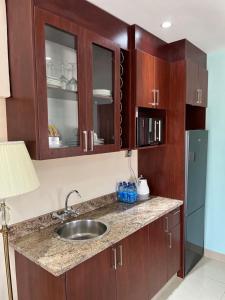 a kitchen with a sink and wooden cabinets and a refrigerator at Open House Hotel in Mbabane