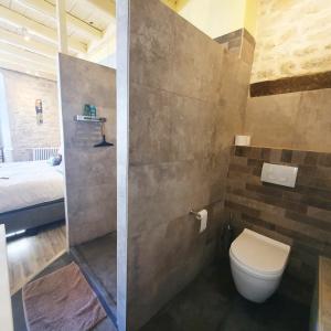 a bathroom with a shower with a toilet and a bed at Maison Fossemagne in Melle