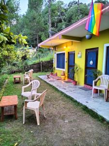 a yellow house with chairs and a rainbow flag at Le Jardin . (The garden) in Almora