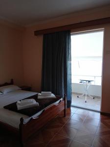 ein Schlafzimmer mit einem Bett, einem großen Fenster und einem Tisch in der Unterkunft FAFALIOS Studios in Vrontádos
