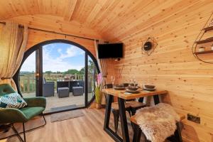 a wooden cabin with a table and a balcony at Blaenplwyf Luxury Countryside Shire Pods with Hot Tubs in Lampeter