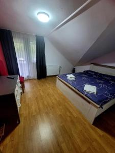 a bedroom with a blue bed and a wooden floor at Casa Delia in Slănic-Moldova