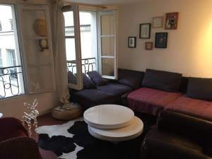 een woonkamer met een bank en een tafel bij Chambres privées dans grand T4-Paris plein-centre in Parijs