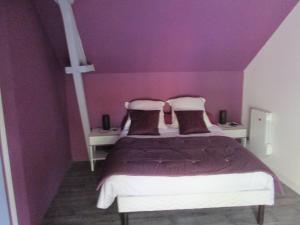 a bedroom with purple walls and a bed with pillows at La Ferme de la Petite Noé in Tracy-sur-Mer