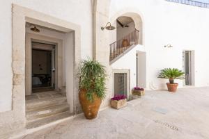 a white building with potted plants and a staircase at Palazzo Angelica BeB Salento - bed and breakfast Otranto in Giurdignano