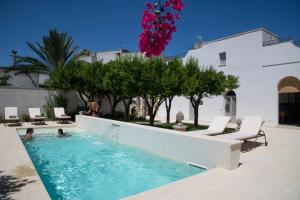 a swimming pool with chairs and trees and a building at Palazzo Angelica BeB Salento - bed and breakfast Otranto in Giurdignano