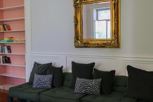 sala de estar con sofá verde y espejo en Rosalma Hostel, en Oporto