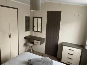 a bedroom with a bed and a desk and a mirror at Bumblebee Lodge in Tintagel