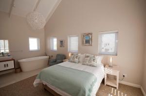 a white bedroom with a bed and a bath tub at Saffron in Knysna