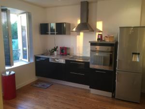 a kitchen with black cabinets and a stainless steel refrigerator at MONTALIEU SEJOUR Appartement les orchidées, 4 pers in Montalieu-Vercieu +3 photos