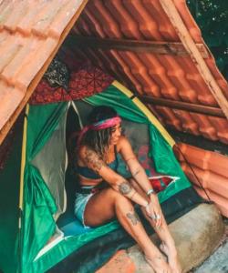 une femme assise à l'intérieur d'une tente dans l'établissement Ready Camp e Suítes da Cachoeira, à Abraão