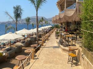 a row of tables and chairs with umbrellas and the water at Sarande Barracuda View Apartment in Sarandë