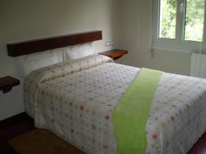 a bedroom with a bed with a green and white comforter at Hotel L'Ablana in Pola de Somiedo