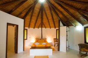 1 dormitorio con 1 cama con techo de madera en Pousada Jardim Cambuí Beach, en Itacimirim