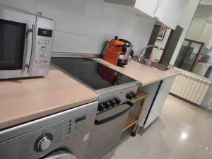 a kitchen with a stove and a microwave at APARTAMENTO PRIVADO CERCA DE IFEMA y AEROPUERTO in Madrid