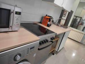 a kitchen with a stove and a microwave at APARTAMENTO PRIVADO CERCA DE IFEMA y AEROPUERTO in Madrid +19 photos