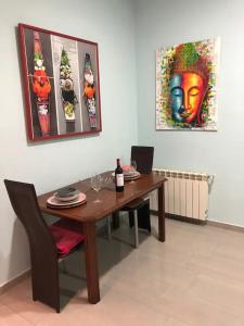 einen Esstisch mit einer Flasche Wein und Gemälden in der Unterkunft APARTAMENTO PRIVADO CERCA DE IFEMA y AEROPUERTO in Madrid