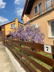 a fence in front of a house with purple flowers at Budapest Airport-Vecsés Trainstation Apartman K7 in Vecsés