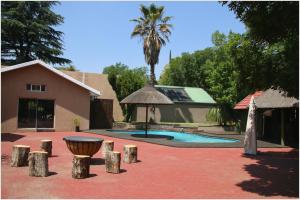 a house with a swimming pool and a palm tree at Aalwyns Guesthouse in Vanderbijlpark