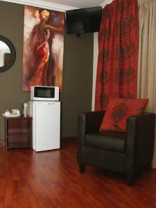 a living room with a chair and a painting on the wall at Aalwyns Guesthouse in Vanderbijlpark