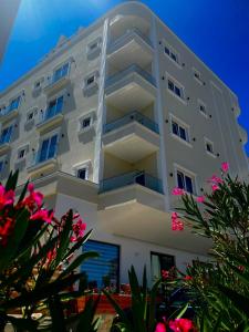 un bâtiment blanc avec des fleurs roses devant lui dans l'établissement Adria Hotel, à Golem