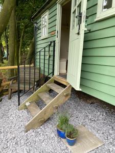 un porche de una casa verde con una puerta y algunas plantas en Lavender Retreat with Private Hot Tub en Upper Hulme